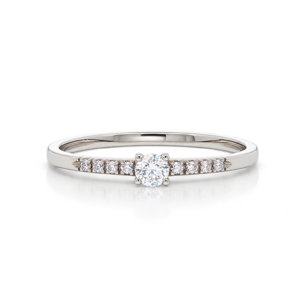 Anillo fino de oro blanco con circonita redonda central en cuatro garras y pequeñas circonitas en ambos brazos
