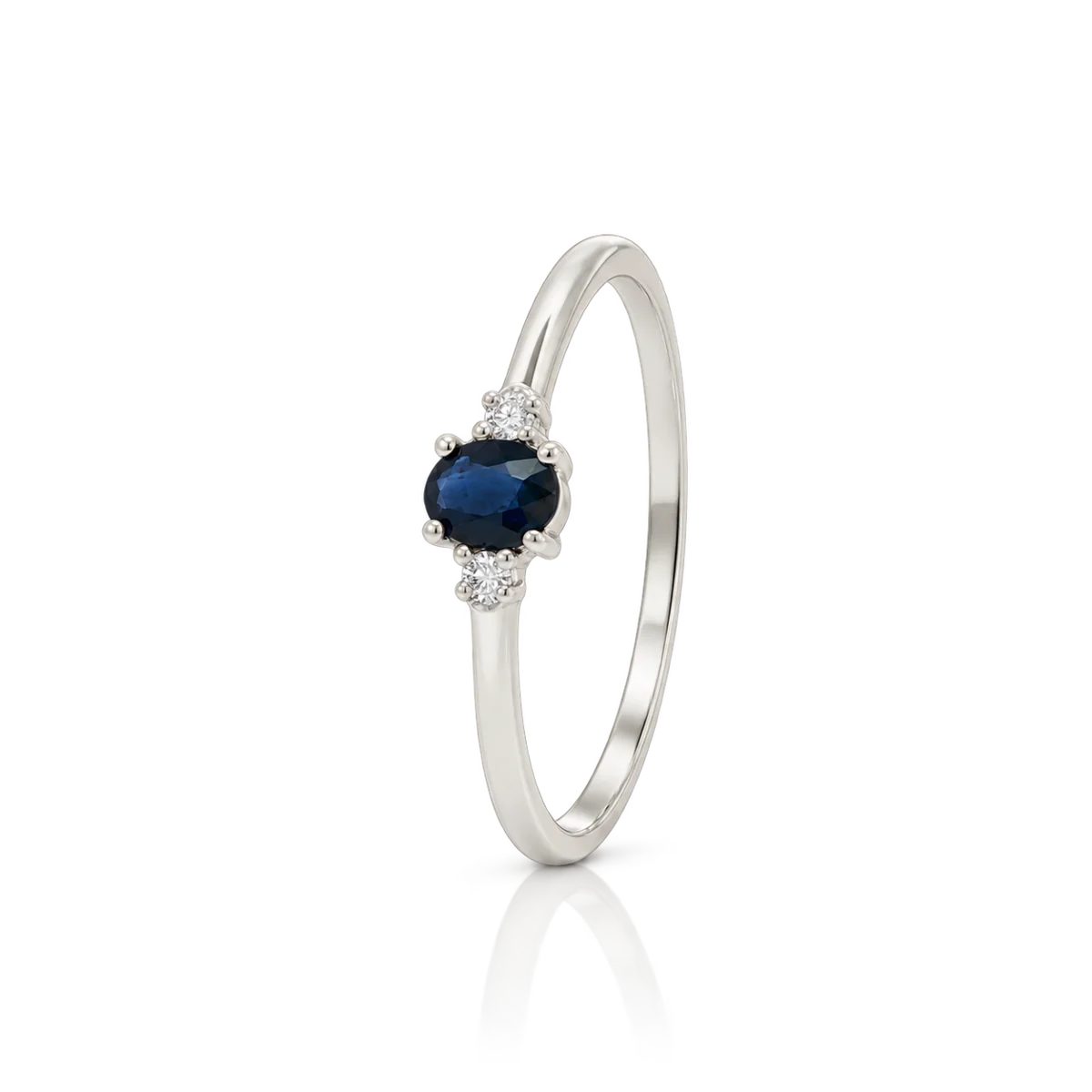Anillo de oro blanco con zafiro oval azul oscuro y diamantes a ambos lados